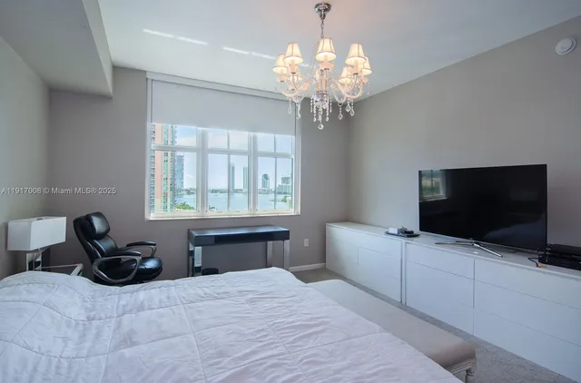 a spacious bedroom with a bed and a flat screen tv