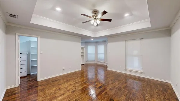 a view of empty room with wooden floor and fan