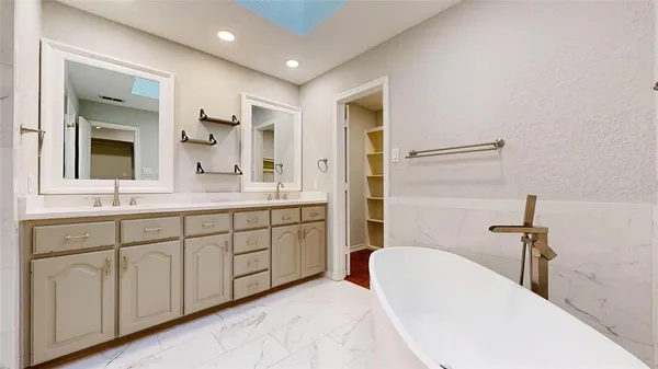 a spacious bathroom with a double vanity sink mirror and bathtub