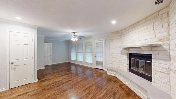an empty room with wooden floor fireplace and windows