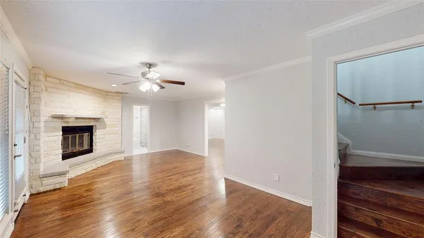 a view of an empty room with wooden floor fireplace and a window