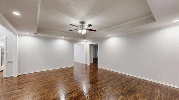 an empty room with wooden floor and a ceiling fan