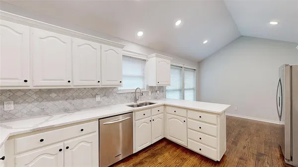 a kitchen with white cabinets and sink