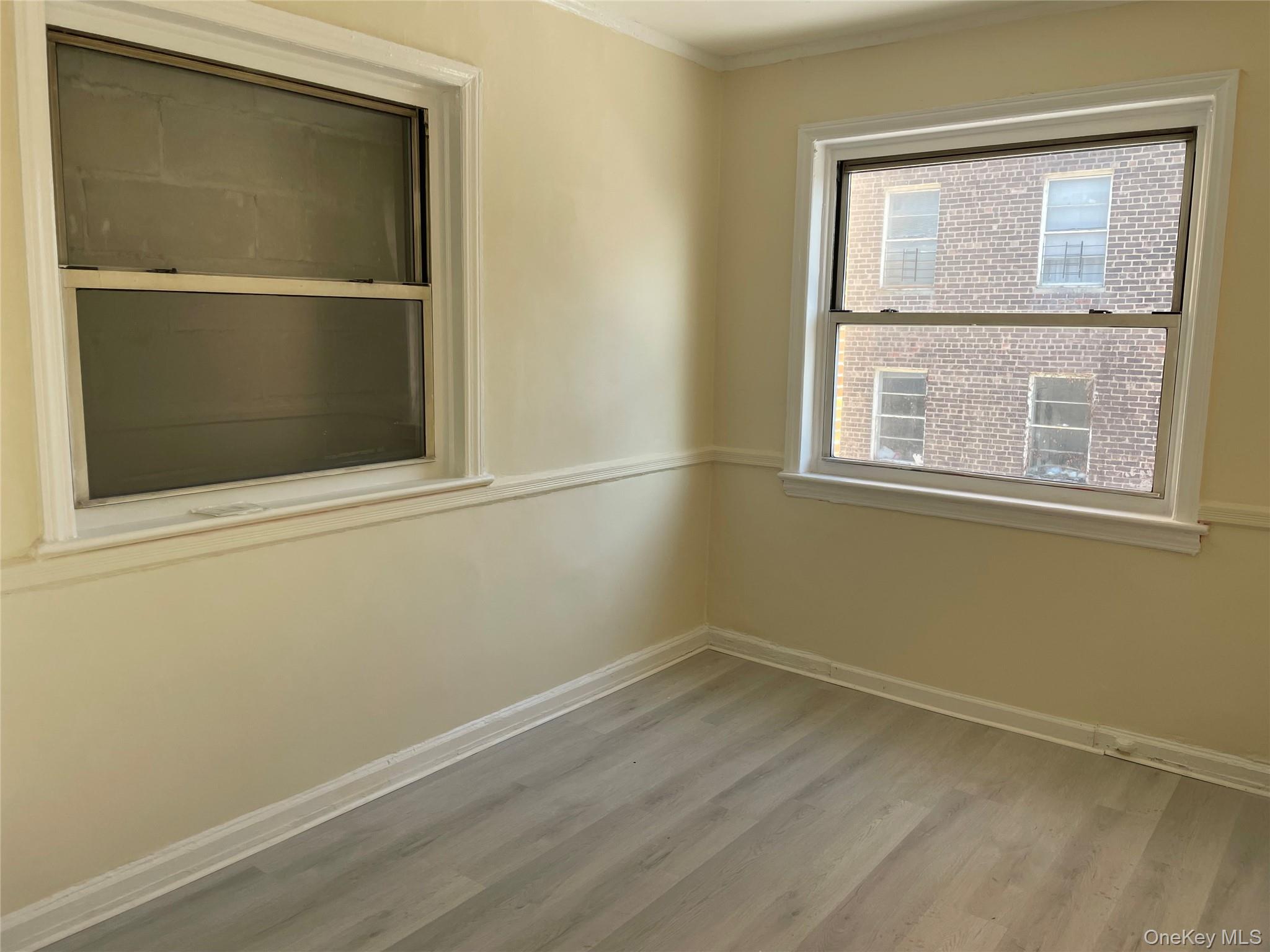 95-12 67th Avenue, Unit 2F Queens, NY 11375 - Photo 2 of 9 Unfurnished room with light wood-style floors and crown molding
