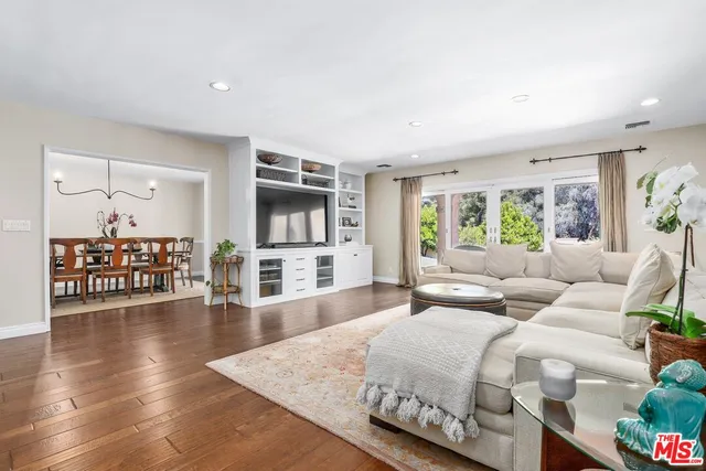 a view of a dining room and livingroom with furniture wooden floor a rug a potted plant and a chandelier