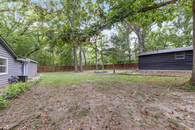 a view of a backyard with wooden fence and large trees