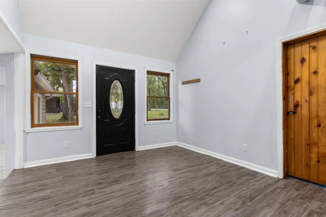 an empty room with wooden floor closet and windows