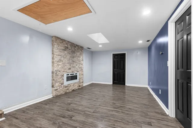 an empty room with wooden floor fireplace and windows