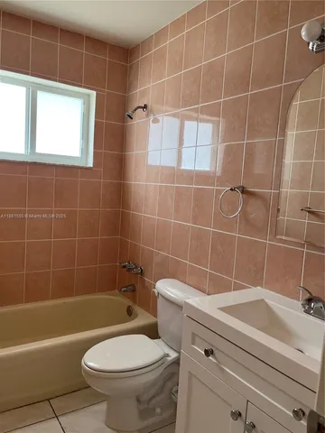 a bathroom with a toilet a sink a window and shower