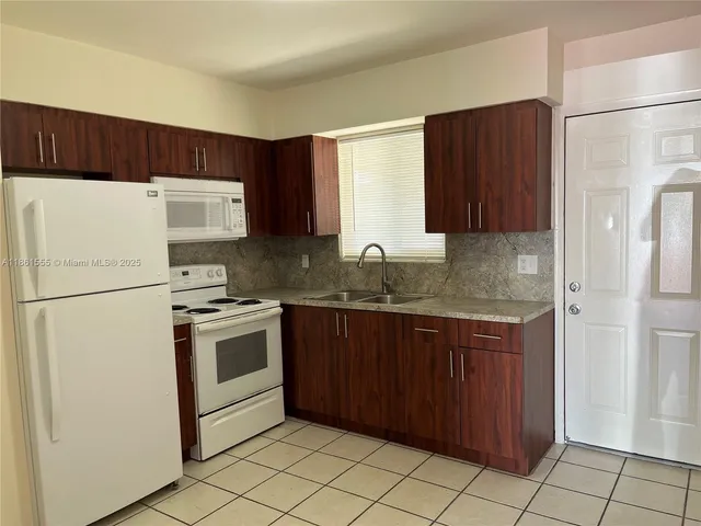a kitchen with granite countertop a refrigerator sink and cabinets