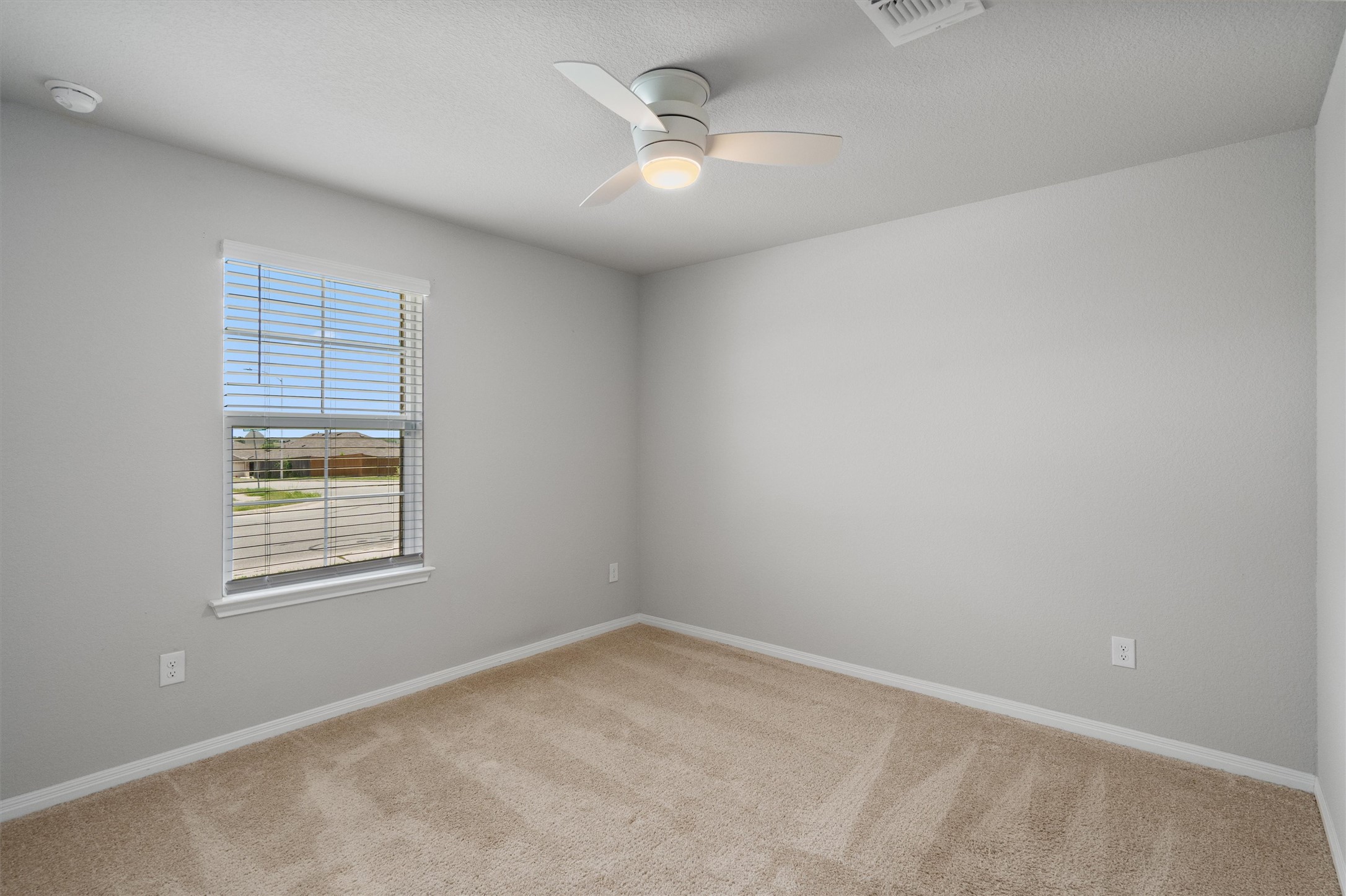 19525 Abigail Fillmore Road Manor, TX 78653 - Photo 20 of 38 A well-lit bedroom offering a peaceful retreat with soft carpet and a modern ceiling fan.