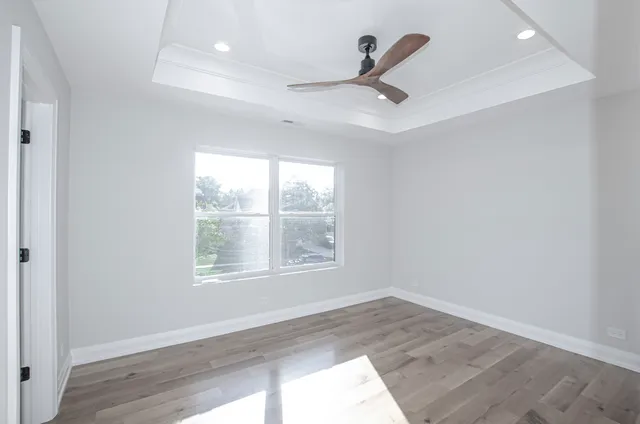 an empty room with wooden floor ceiling fan and windows