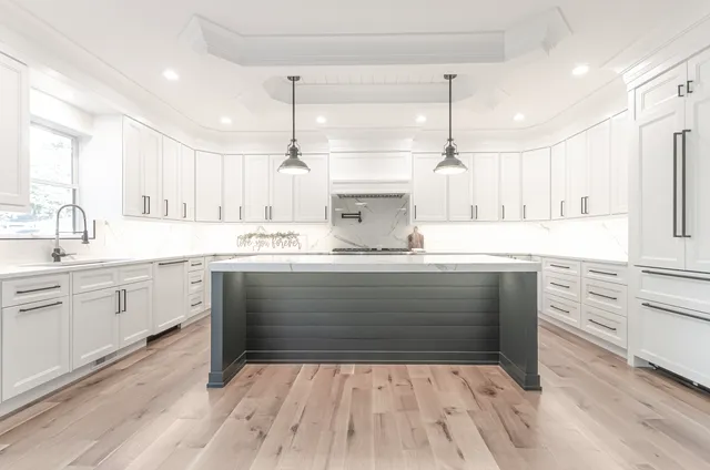 a kitchen with a sink dishwasher a stove and white cabinets with wooden floor