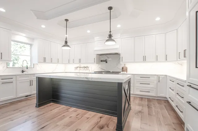 a kitchen with kitchen island white cabinets appliances and a chandelier