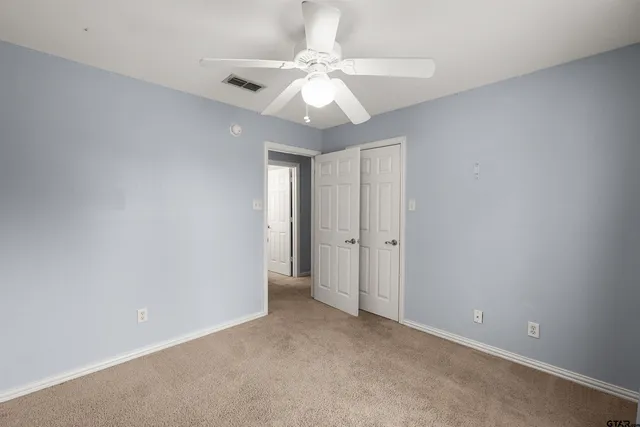 a view of an empty room and chandelier fan