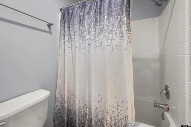 a bathroom with a shower curtain and a toilet