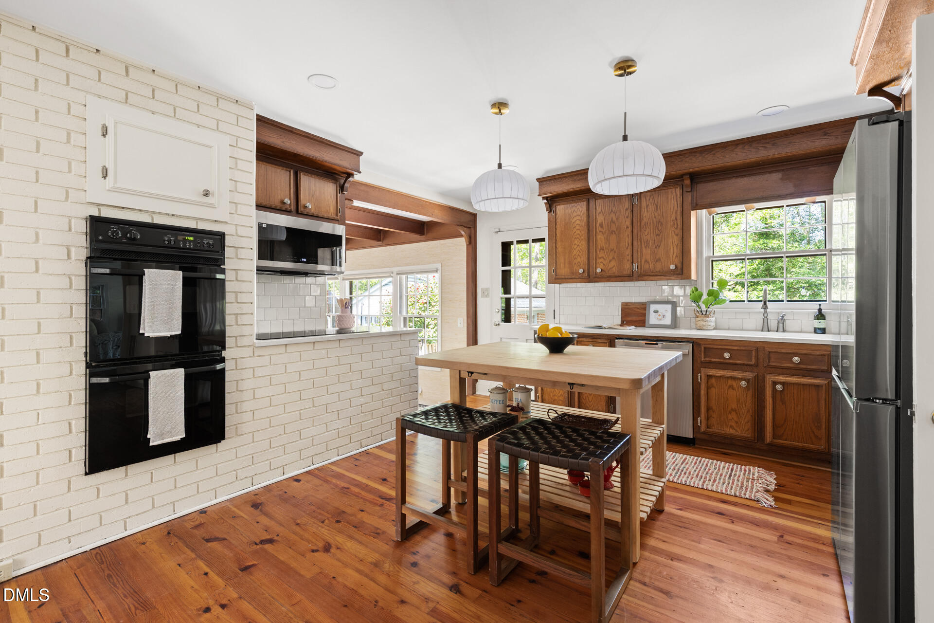 1706 Wallace Street Durham, NC 27707 - Photo 20 of 55 a kitchen with stainless steel appliances granite countertop a stove a refrigerator a oven a sink with a dining table and chairs with wooden floor