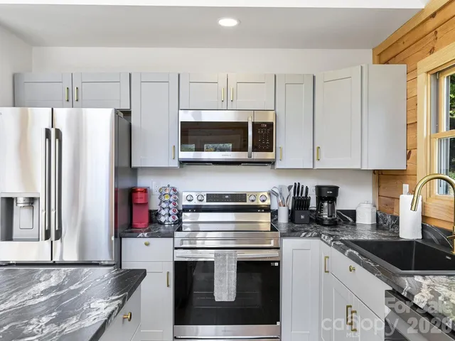 a kitchen with granite countertop a refrigerator stove and microwave