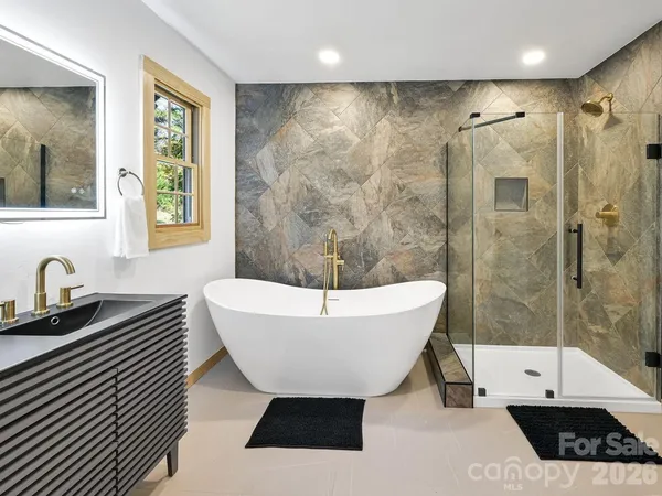 a bathroom with a sink a bathtub a window and a shower