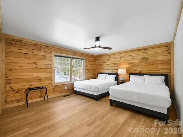 a spacious bedroom with a bed and wooden floor