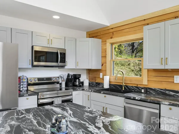 a kitchen with stainless steel appliances granite countertop a stove a sink and a microwave