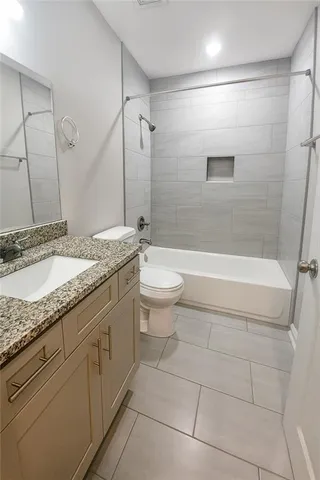 a bathroom with a granite countertop sink mirror toilet and bathtub