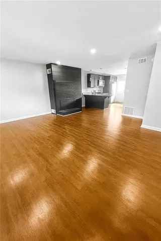 a view of kitchen and empty room with wooden floor