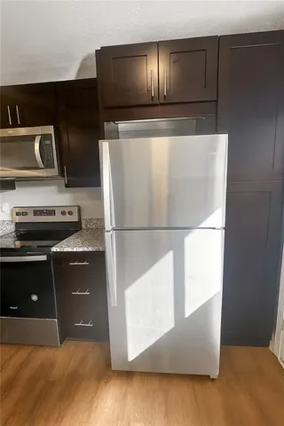 a kitchen with kitchen island granite countertop a refrigerator and a stove