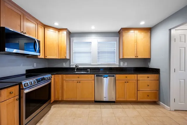 a kitchen with stainless steel appliances granite countertop wooden cabinets a stove a sink and dishwasher