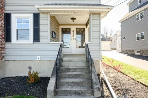 a view of a house with large windows and plants