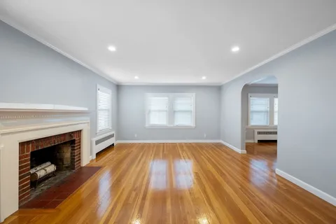 a view of empty room with wooden floor and fireplace