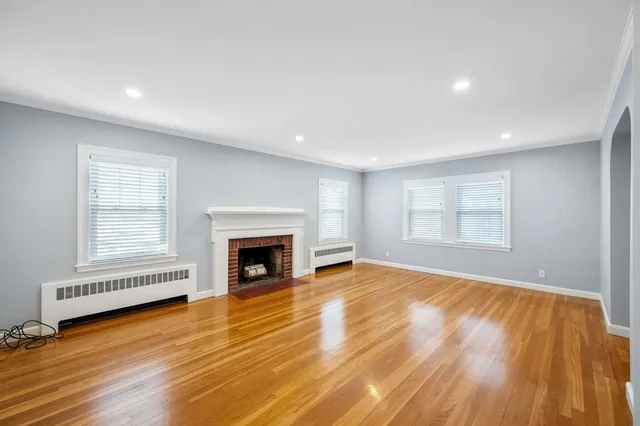 an empty room with wooden floor fireplace and windows