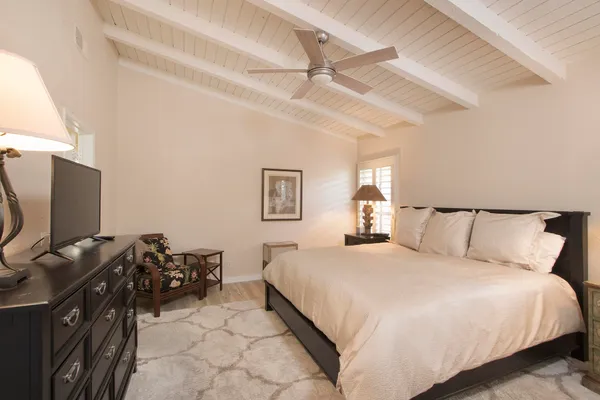 a living room with a flat screen tv on dresser and a table