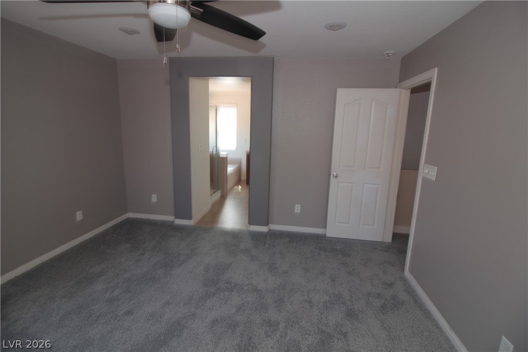 9289 Valley Ranch Avenue Las Vegas, NV 89178 - Photo 21 of 29 A spacious primary bedroom featuring plush carpeting and a convenient ceiling fan for comfort.