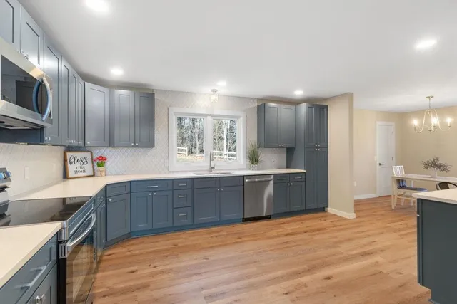 a large kitchen with stainless steel appliances kitchen island granite countertop a sink and cabinets
