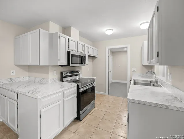 a kitchen with stainless steel appliances granite countertop a sink stove oven and white cabinets