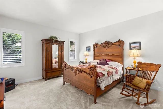 a bed sitting in a bedroom next to a window and a chair