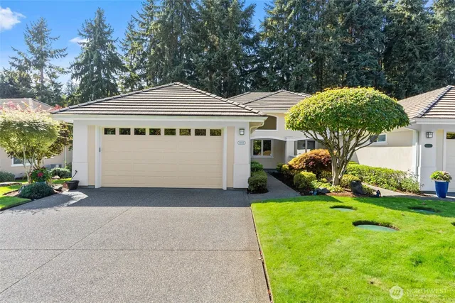 a view of a white house with a big yard plants and large trees