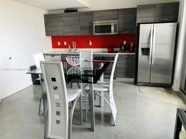 a kitchen with stainless steel appliances a refrigerator a stove a dining table and chairs