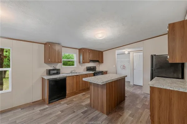a kitchen with stainless steel appliances granite countertop a stove top oven a sink dishwasher and a refrigerator