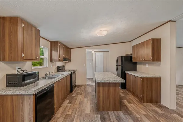 a kitchen with stainless steel appliances granite countertop wooden cabinets a stove top oven a sink and dishwasher with wooden floor