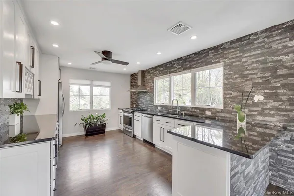 a large kitchen with stainless steel appliances granite countertop a stove a sink and a refrigerator