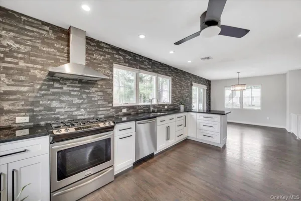 a large kitchen with stainless steel appliances granite countertop a stove and a wooden floors