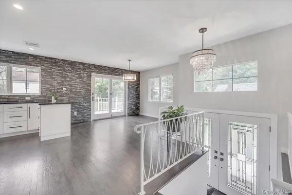 a view of an empty room and kitchen with wooden floor