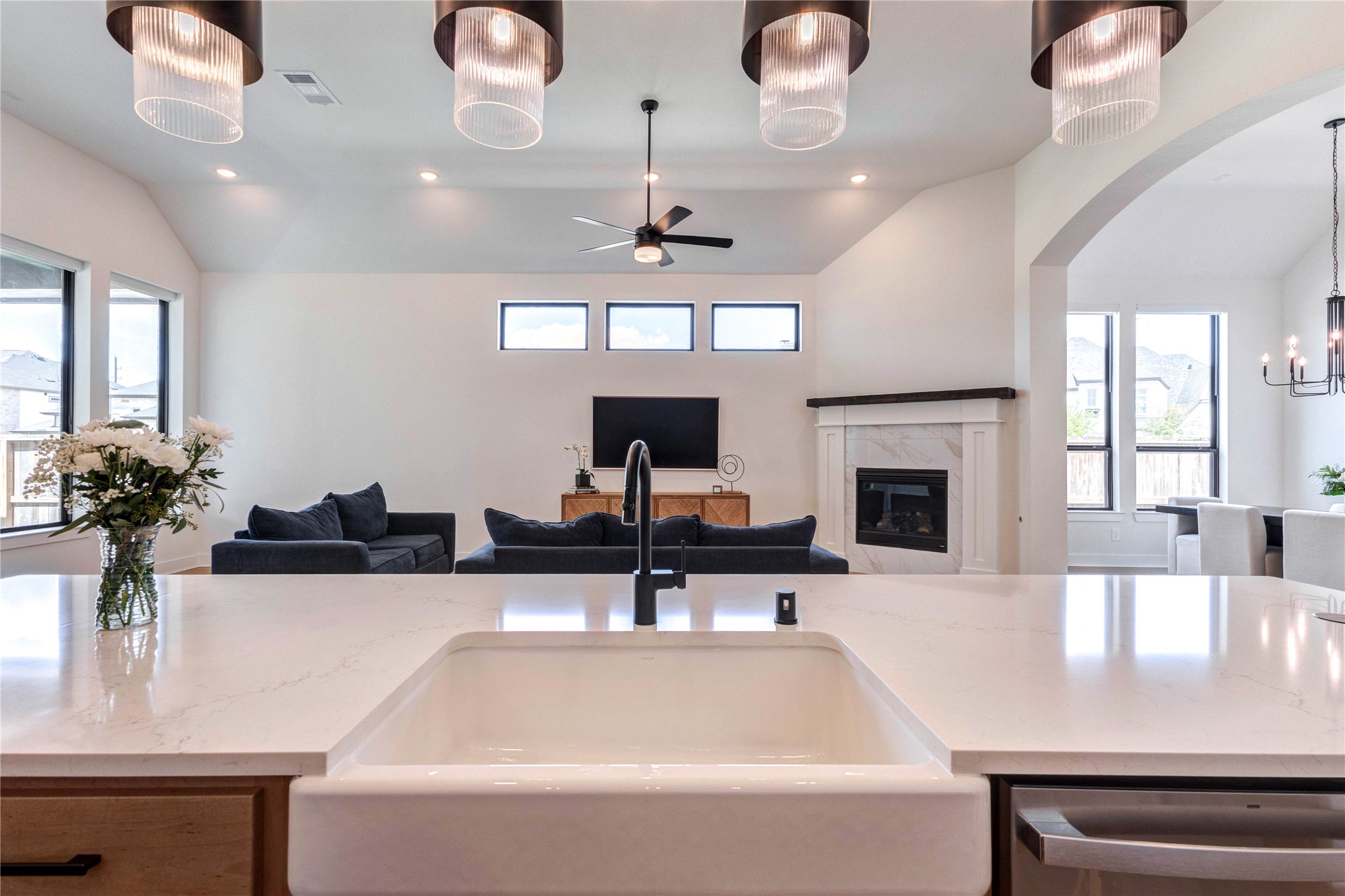 4510 Windmill Lndg Lane Fulshear, TX 77441 - Photo 14 of 48 This modern kitchen features sleek, dual-tone cabinetry with ample storage, a large island with a farmhouse sink, stainless steel appliances, and elegant pendant lighting. The open layout extends to a dining area with natural light and a stylish chandelier.