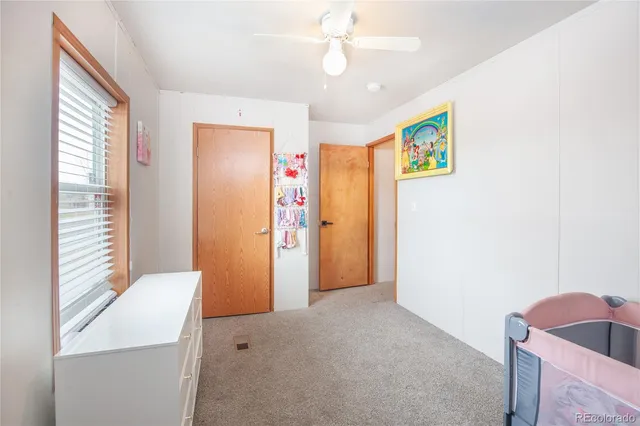 a view of an empty room with window and chandelier fan