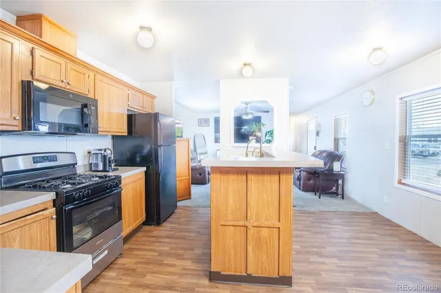 a kitchen with stainless steel appliances granite countertop a stove top oven a sink dishwasher a refrigerator and a dining table with wooden floor