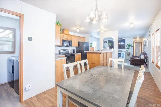 a living room with stainless steel appliances furniture a rug and a kitchen view
