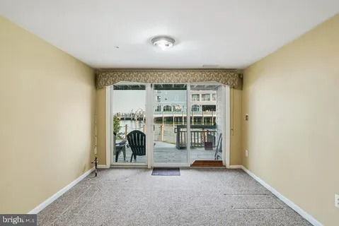 an empty room with floor to ceiling window and ceiling fan