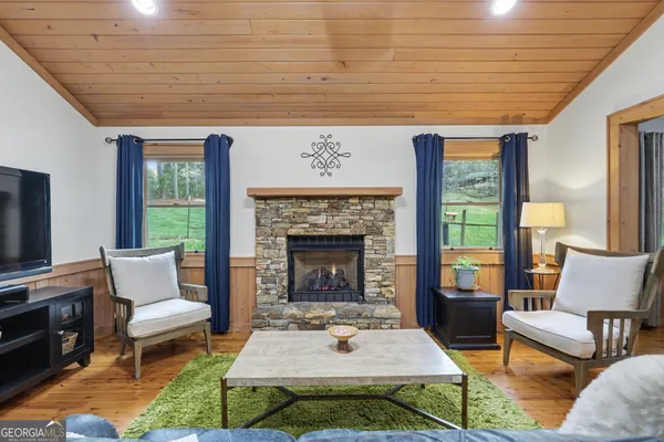 a living room with furniture a rug a fireplace and a large window